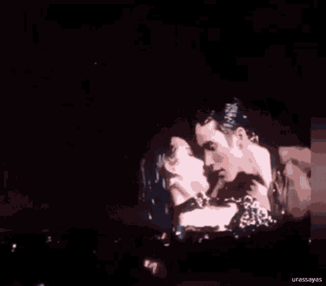 a man and a woman are kissing in front of a crowd at a concert .