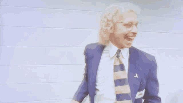 a man in a blue jacket and tie has a name tag that says ' a. ' on it