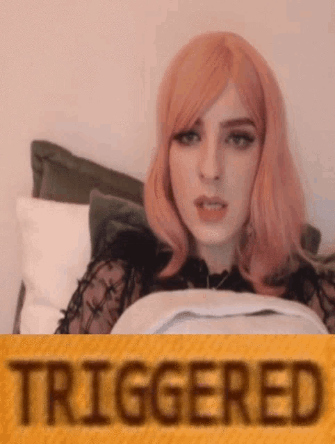 a woman with pink hair is laying on a bed with the word triggered written on a yellow background