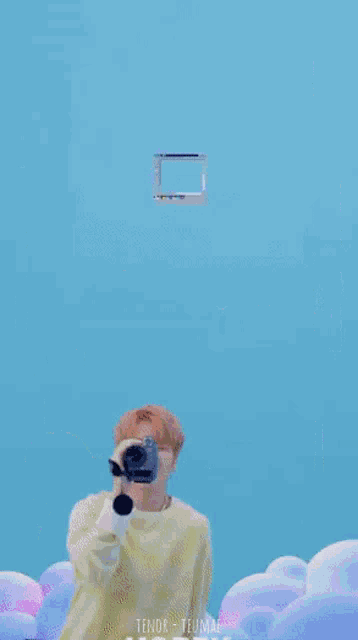a man is holding a camera in front of a computer screen that says paint