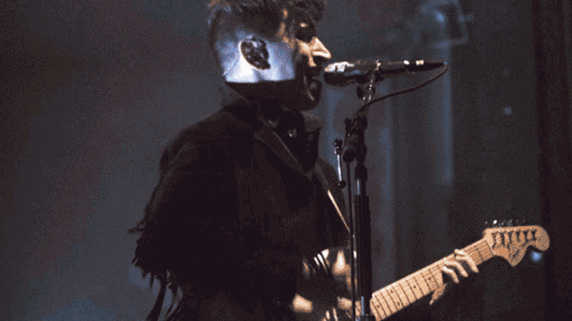 a man is singing into a microphone while holding a guitar