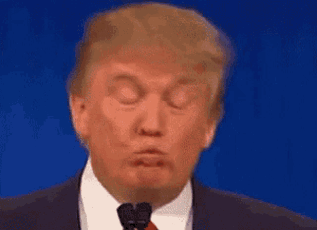 donald trump is making a funny face while giving a speech .