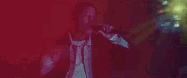 a woman is standing in a dark room with a green light shining on her face .