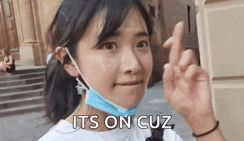 a woman wearing a mask is making a heart shape with her fingers and the words `` its on cuz '' behind her .