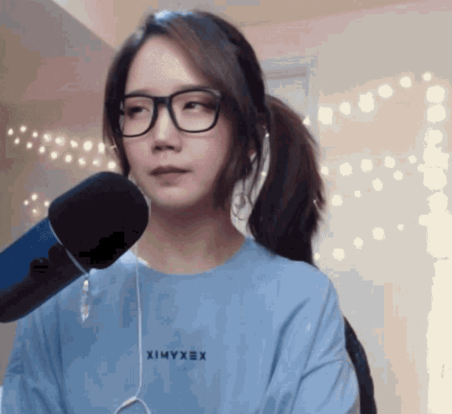 a woman wearing glasses and a blue shirt with the word ximyxex on it
