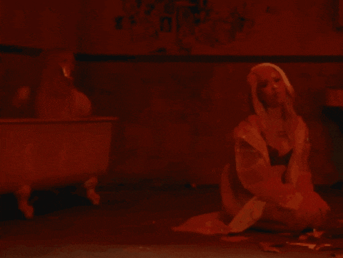 a woman sitting on the floor in front of a bathtub