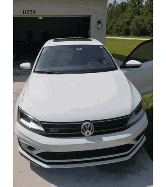a white volkswagen is parked in front of a garage
