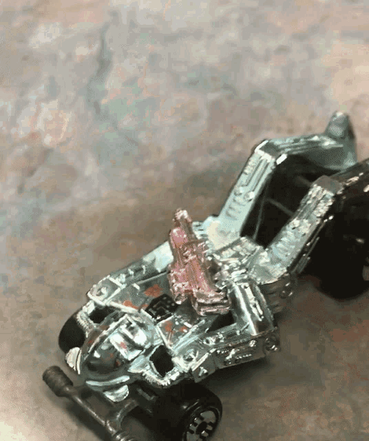 a silver toy car with a pink engine is sitting on a table