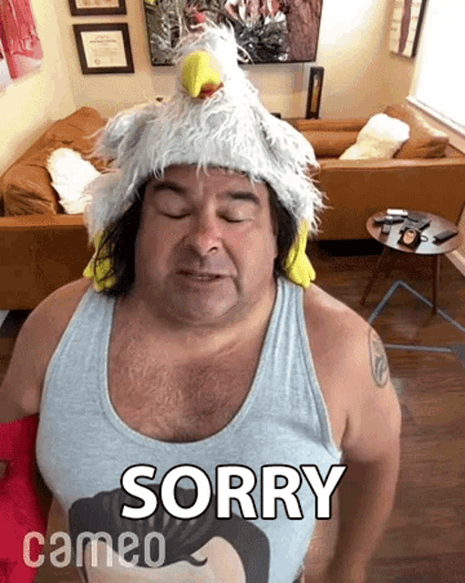 a man wearing a chicken hat and a cameo shirt is saying sorry .