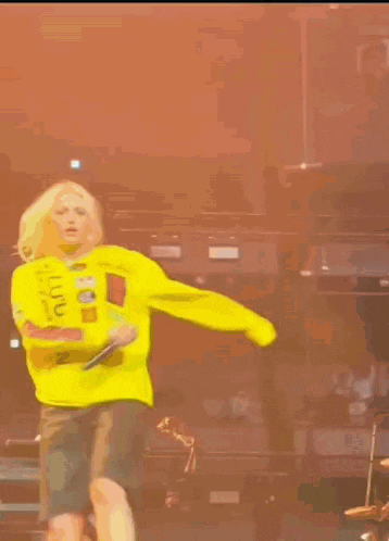 a person in a yellow shirt is dancing on a stage in front of a keyboard .
