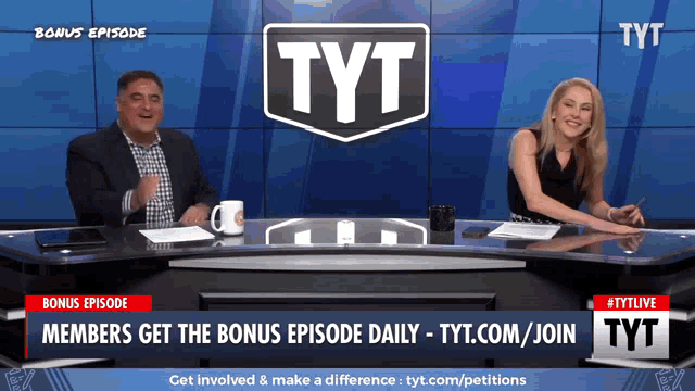 a man and a woman sit at a desk in front of a screen that says tyt