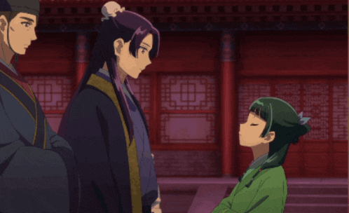 a girl in a green dress is talking to a man in a black robe
