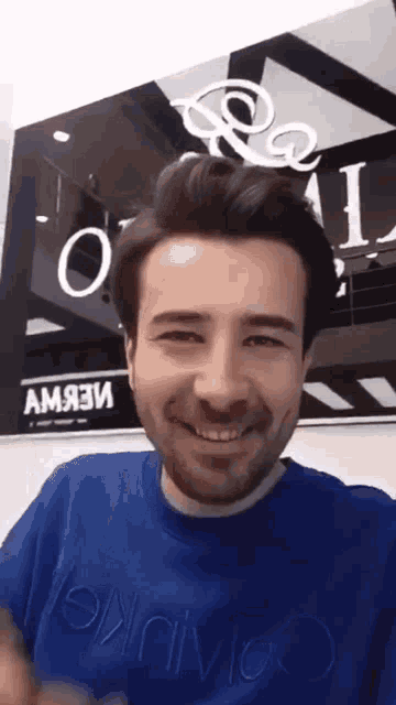 a man wearing a blue shirt that says calvin klein is smiling