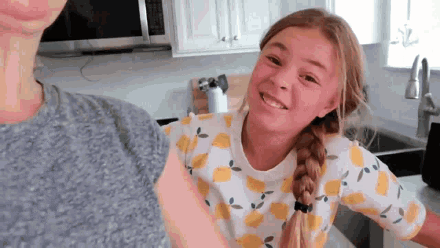 a little girl wearing a shirt with lemons on it smiles at the camera