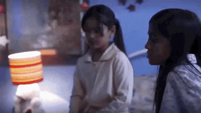 two young girls are standing next to each other in a bedroom .