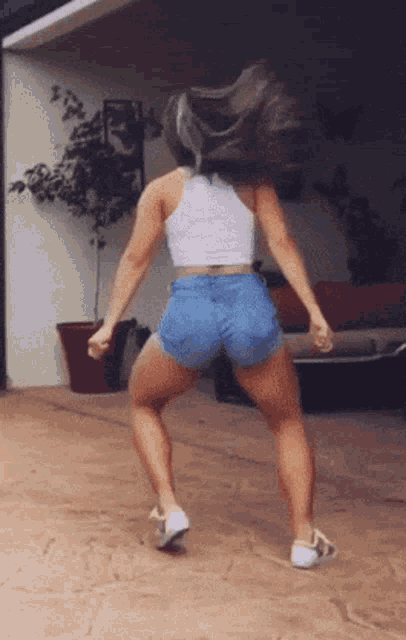 a woman in shorts and a white tank top dancing