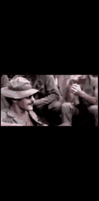 a group of soldiers are sitting on the ground talking to each other in a dark room .