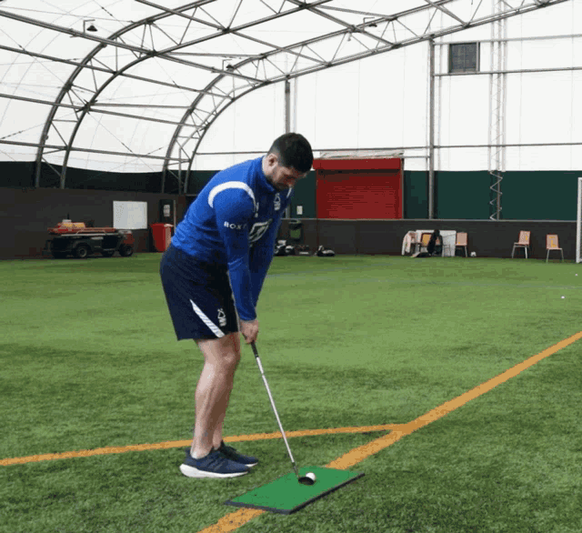 a man wearing a blue shirt that says bca on it playing golf