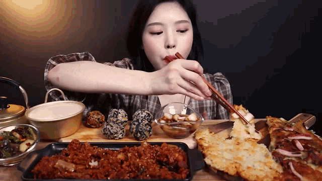 a woman is eating a tray of food with chopsticks ..