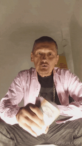 a man in a pink shirt is holding a bunch of money in his hands