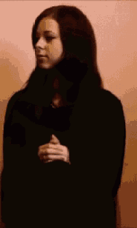 a woman in a black dress is laughing and giving a middle finger .