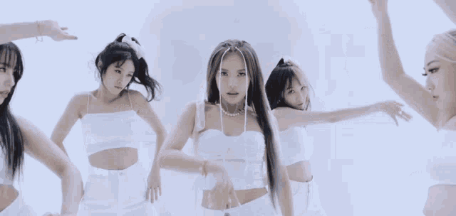 a group of women in white crop tops are dancing in front of a white wall