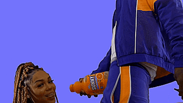a man is giving a woman a bottle of sunny orange drink