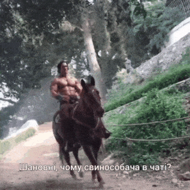 a man without a shirt is riding a horse on a dirt road with trees in the background