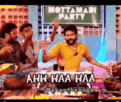 a group of men are sitting around a table with a sign that says mottamadi party behind them .