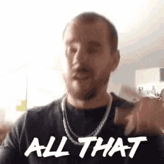 a man with a beard is wearing a necklace and a black shirt and says `` all that '' .