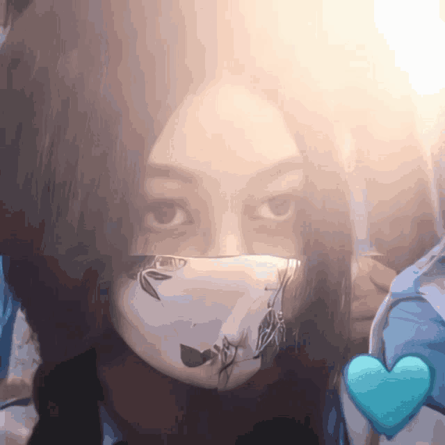 a woman wearing a face mask with a blue heart in the background