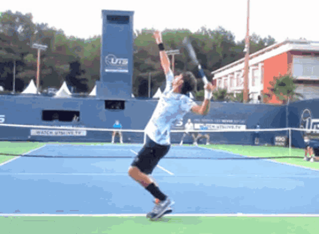 a man is jumping in the air while holding a tennis racquet in front of a uts sign