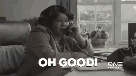 a woman is sitting at a desk talking on a telephone while wearing headphones .