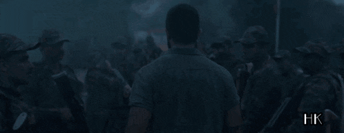 a man stands in front of a group of soldiers with xhk written on the bottom right