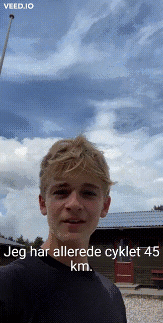 a young man is standing in front of a building with the words jeg har allerede cyklet 45 km written below him