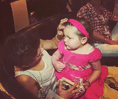 a little girl in a pink dress is being held by a woman in a white tank top