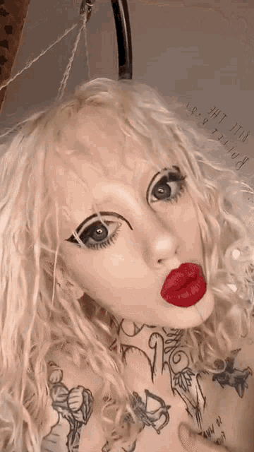 a woman with blonde hair and red lipstick has a tattoo on her chest