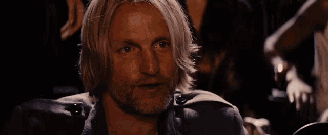 a man with blonde hair and a beard is holding a bottle in his hand