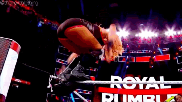 a woman is jumping over a rope in a wrestling ring with the words royal rumble in the background .