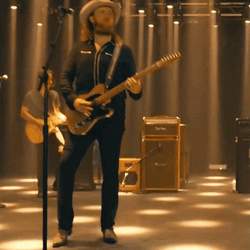 a man in a cowboy hat playing a guitar