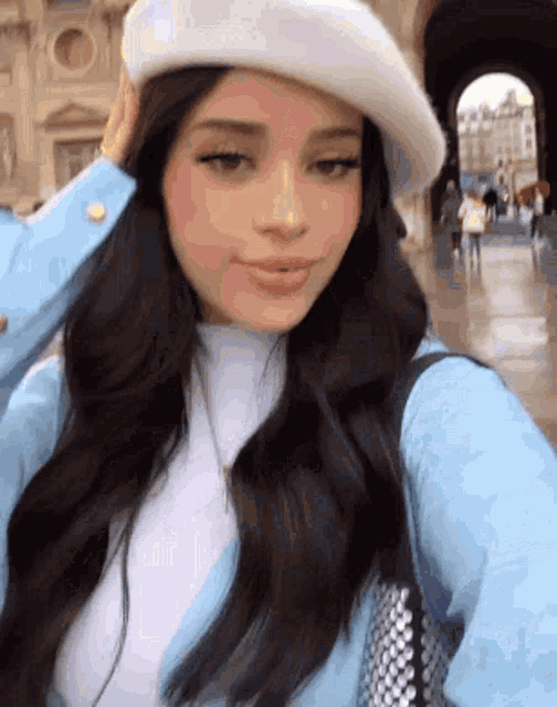 a woman is wearing a white beret and taking a selfie .