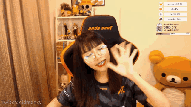 a girl with braces on her teeth sits in an orange and black chair with the word anda seal on it