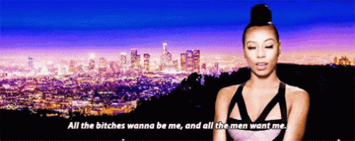a woman says " all the bitches wanna be me " in front of a city skyline