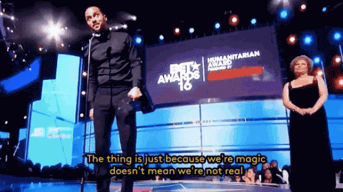 a man stands in front of a large screen that says beta awards
