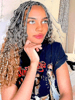 a young woman with braids and curly hair is sitting on a bed .