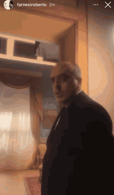 a man in a suit and tie is standing in a room with the name farnesiroberto on the bottom