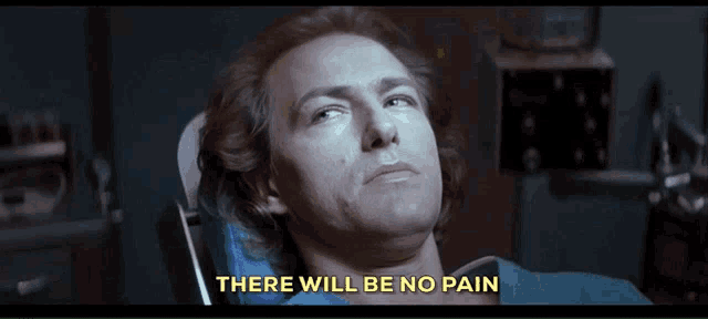 a man laying in a dental chair with the words " there will be no pain " above him