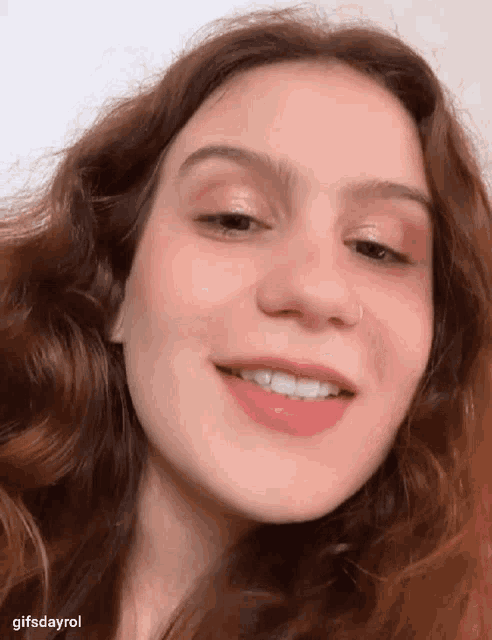a woman with red hair and a nose ring smiles