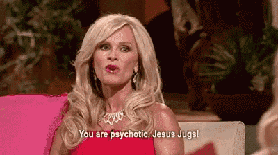 a woman in a red dress is sitting on a pink couch and saying `` you are psychotic , jesus jugs '' .