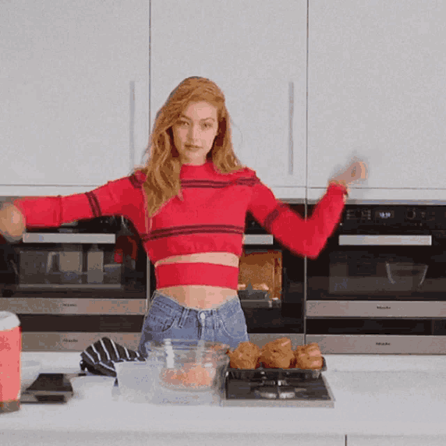 a woman in a red sweater is cooking in a kitchen with a miele oven